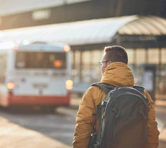 Ein junger Mann mit Rucksack läuft auf eine Bushaltestelle zu