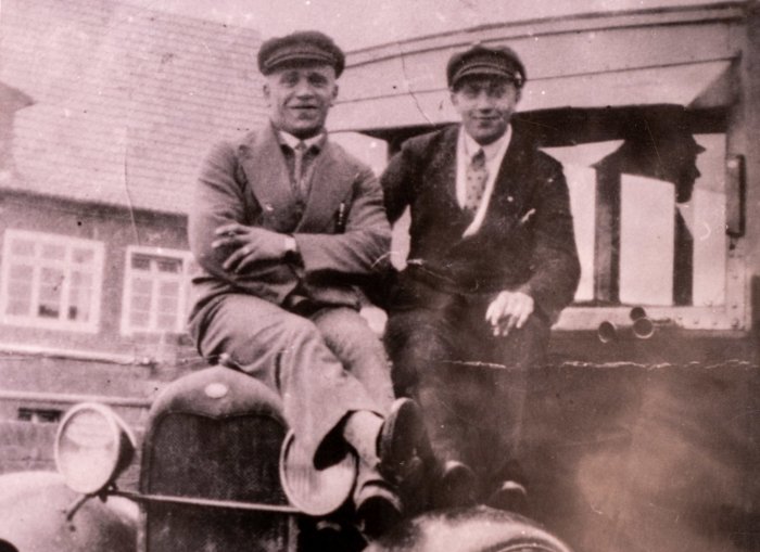 1930 Zwei Männer in Anzügen auf der Motorhaube eines alten Busses